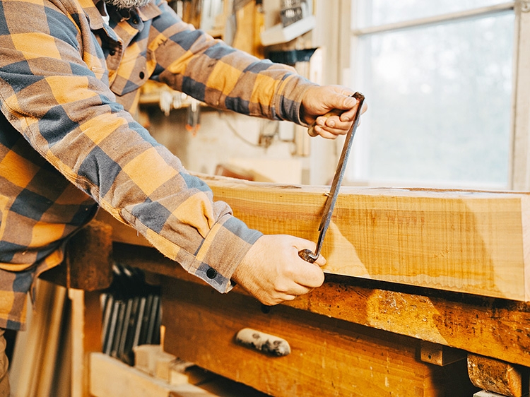 Holzhandwerk Kohler Ein Mann bearbeitet einen Holzstamm.