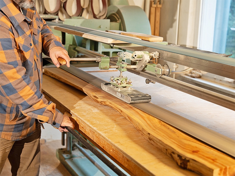 Holzhandwerk Kohler Ein Mann bearbeitet einen Holzstamm.
